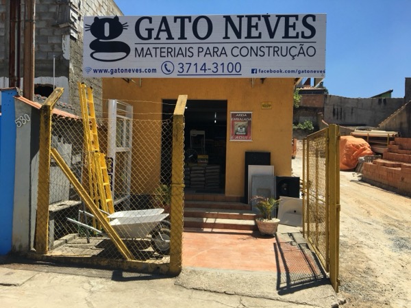 Entrada da loja Gato Neves com placa branca e parede amarela, vista da rua